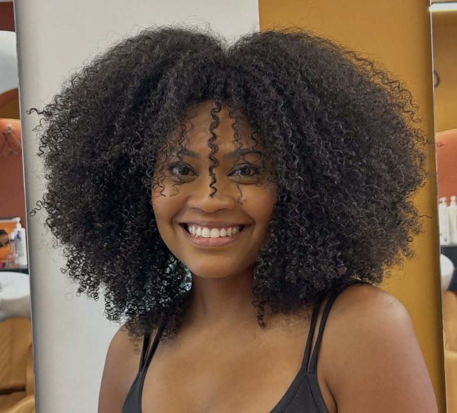 Cliente sorrindo com afro volumoso e definido